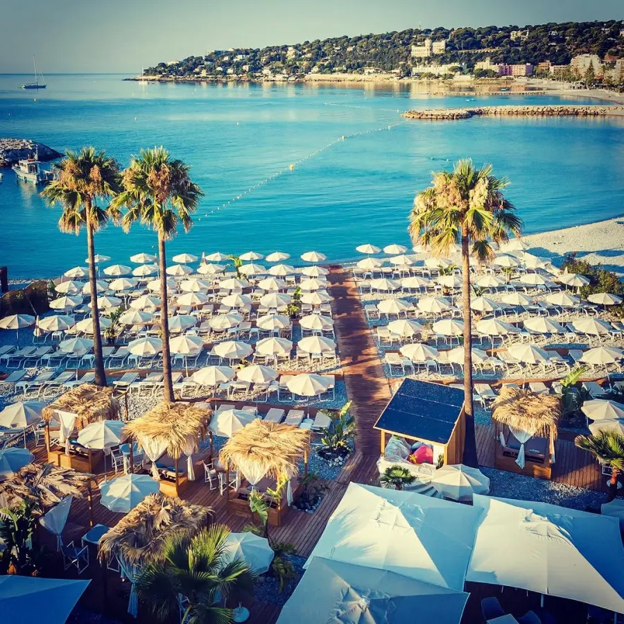 Private beach, parasols and palm trees at Roquebrune-Cap-Martin, seen from a drone